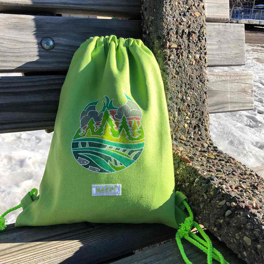 Limegreen Hodag backpack with colored in artwork on a park bench
