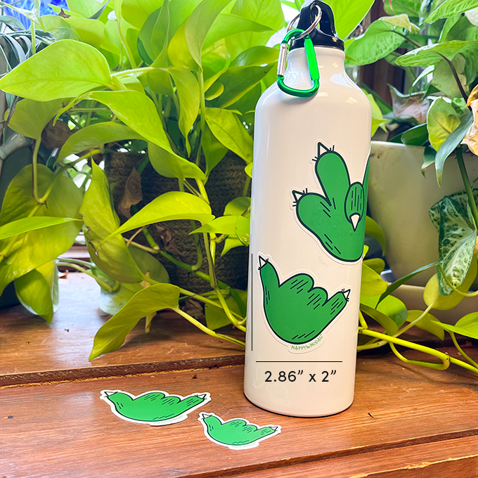 Green paw making the "hang loose" or Shaka gesture stickers laying on on a table and stuck on a bottle