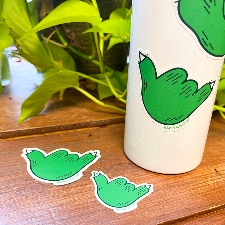 Green paw making the "hang loose" or Shaka gesture stickers laying on on a table and stuck on a bottle