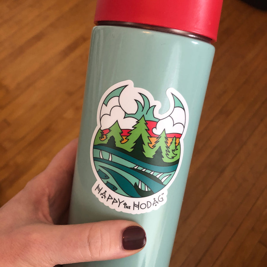 Sticker shaped like Happy the hod's head with colorful artwork of sky, trees, water and a Meshipeshu hiding in the waves with the text Happy the Hodag shown applied to water bottle