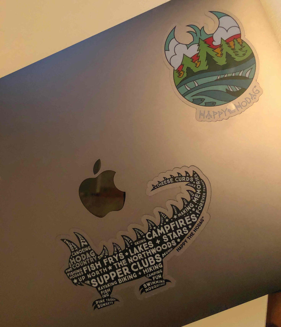 Black Hodag silhouette sticker with white words including 'amores, canoeing, pine trees, fishing, fish frys, up north, lakes+stars, campfires, supper clubs, kayaking, biking + hiking. Sticker shown on a laptop cover.
